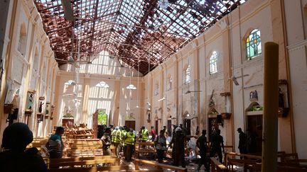 Des policiers&nbsp;inspectent l'église Saint-Sébastien à&nbsp;Negombo, une localité au nord de Colombo, après l'explosion d'une bombe.&nbsp; (STRINGER / REUTERS)