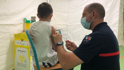 Un enfant se fait vacciner par un pompier à Thenon (Dordogne). (LISE ROOS-WEIL / RADIO FRANCE)