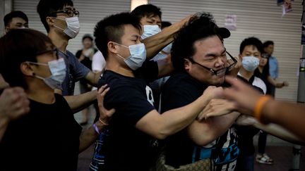 Un manifestant pro-d&eacute;mocratie est frapp&eacute; par un groupe d'hommes masqu&eacute;s, &agrave; Causeway Bay (Hong Kong), le 3 octobre 2014. (ALEX OGLE / AFP)