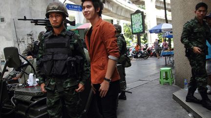 Un jeune homme pose au c&ocirc;t&eacute; d'un soldat de l'arm&eacute;e royale tha&iuml;landaise &agrave; Bangkok (Tha&iuml;lande), le 20 mai 2014. (PITI A. SAHAKOM / LIGHTROCKET / GETTY IMAGES)