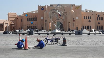 Deux ouvriers africains&nbsp;cassent des pavés dans le quartier touristique de Katara, à Doha (Qatar), le 17 novembre 2022, à quelques jours du lancement du Mondial de foot.&nbsp; (FARIDA NOUAR / RADIO FRANCE)