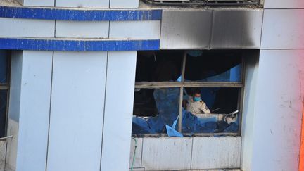 Un policier indien inspecte un hôpital détruit par un incendie à Bombay, le 23 avril 2021.&nbsp; (SACHIN HALDE / ANADOLU AGENCY / AFP)