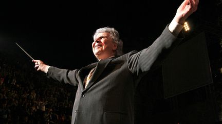 Le célèbre compositeur Mikis Theodorakis dirigeant son orchestre lors d'un concert de gala au théâtre antique Herodus Atticus à Athènes, en 2005. (LOUISA GOULIAMAKI / AFP)