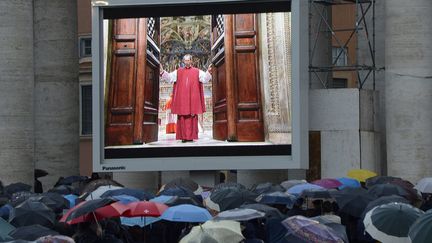 Des fid&egrave;les observent,&nbsp;sur un &eacute;cran g&eacute;ant install&eacute; sur la place Saint-Pierre, la porte de la chapelle Sixtine se refermer sur le conclave, Vatican, le 12 mars 2013. (ANDREAS SOLARO / AFP)