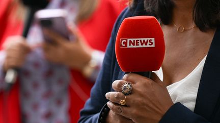 Une journaliste tient un micro de la chaîne CNews, le 17 juillet 2024, devant l'Elysée à Paris. (ARTUR WIDAK / NURPHOTO / AFP)