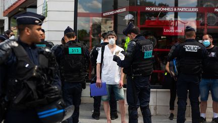 Des policiers contrôlent l'identité de manifestants réclamant plus de moyens pour les soignants, le 21 mai 2020, à Paris. (RAPHAEL KESSLER / HANS LUCAS / AFP)