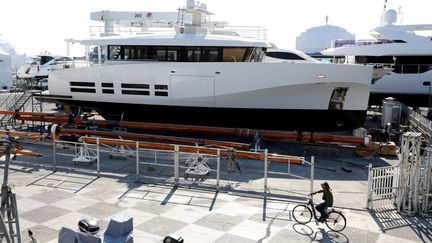 Un cycliste passe devant le yacht "La Petite Ourse" de l'oligarque russe Alexei Kuzmichev, saisi par les autorités françaises et ici à quai dans le port d'Antibes, le 24 mars 2022.&nbsp; (VALERY HACHE / AFP)