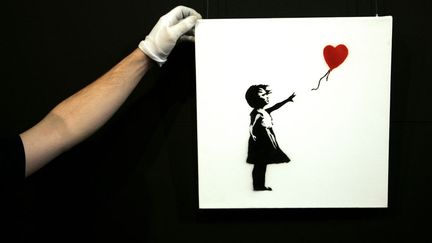 Un employ&eacute; redresse le tableau de Banksy "Balloon Girl", pr&eacute;sent&eacute; au public avant d'&ecirc;tre mis aux ench&egrave;res &agrave; Londres (Royaume-Uni), le 2 f&eacute;vrier 2007. (LUKE MACGREGOR / REUTERS)