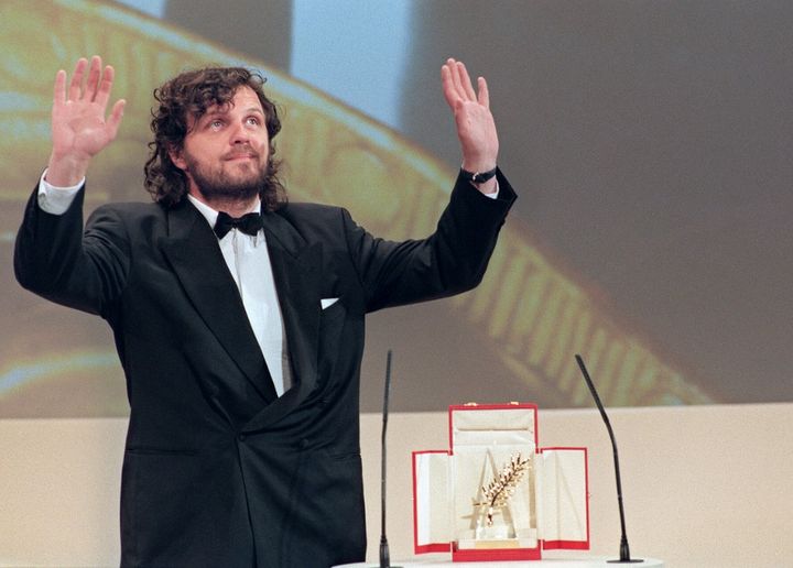 Le réalisateur Emir Kusturica salue le public après avoir reçu la Palme d'or pour son film "Underground", le 28 mai 1995, lors du 48e Festival de Cannes. (PATRICK HERTZOG / AFP)