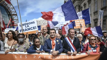 Le dirigeant des Patriotes, Florian Philippot (au centre), et le le chef de Debout la France, Nicolas Dupont-Aignan, défilent lors d'une manifestation contre le pass sanitaire près de l'Ecole militaire, à Paris, le 7 août 2021. (STEPHANE DE SAKUTIN / AFP)