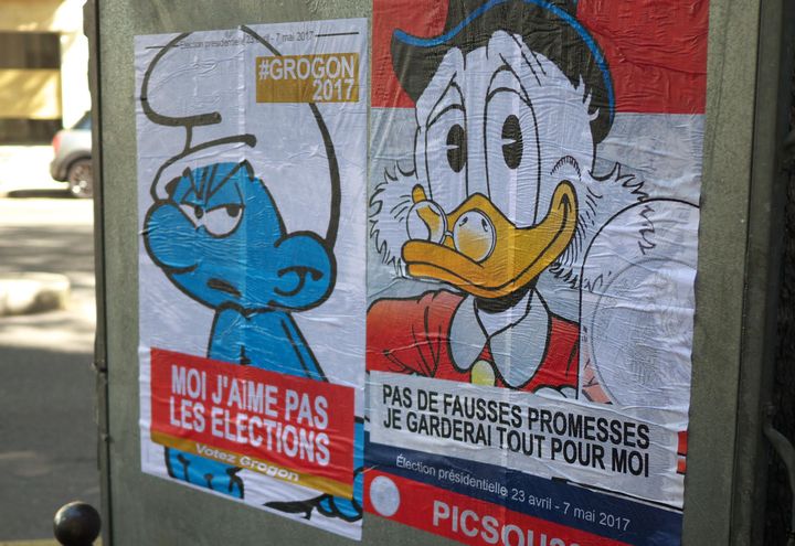 Le street-artist Combo a parodié les affiches de la campagne présidentielle avec, ici, les candidatures du Schtroumpf Grognon et de Picsou,&nbsp;collées à Paris en avril 2017. (CLAUDE DEGOUTTE / JAERAYMIE / COMBO)