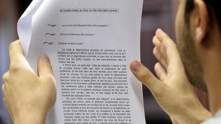 Un bachelier fran&ccedil;ais tient le sujet de l'&eacute;preuve de philosophie du bac g&eacute;n&eacute;ral, lundi 16 juin 2014.&nbsp; (FREDERICK FLORIN / AFP)