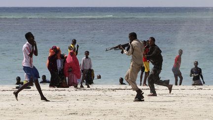 Un officier de police somalien (D) arr&ecirc;te un rebelle suspect&eacute; d'appartenir &agrave; Al Qaeda sur la plage de Lido &agrave; Mogadishu (Somalie), le 23 mars 2012. (FEISAL OMAR / REUTERS)