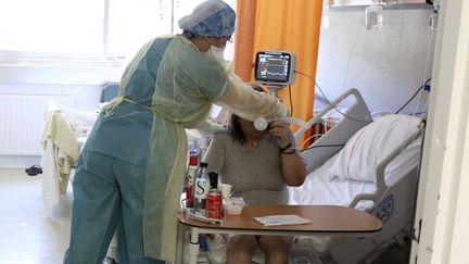 Un soignant s'occupe d'une patiente dans une unité pour malades du Covid-19, à l'hôpital de Bastia, le 5 août 2021.&nbsp; (PASCAL POCHARD-CASABIANCA / AFP)