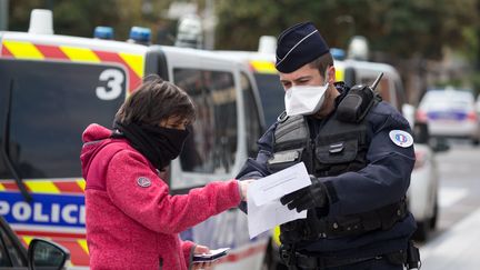 Un fonctionnaire de police contrôle une passante, dans une rue de Toulouse (Haute-Garonne), le 17 mars 2020.&nbsp; (FREDERIC SCHEIBER / HANS LUCAS / AFP)