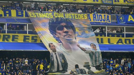 Les supporters de Boca Juniors affichent une photo géante de la légende du football argentin Diego Maradona, le 24 juillet 2024, à Buenos Aires. (JUAN MABROMATA / AFP)