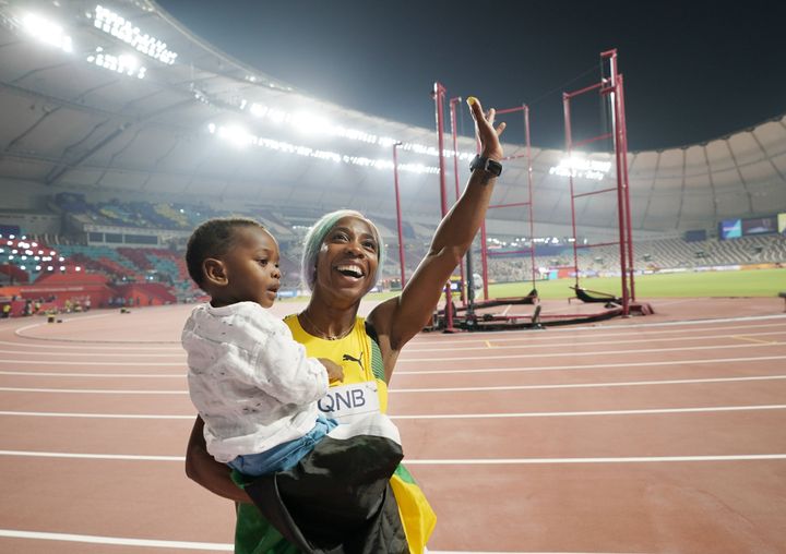 Shelly-Ann Fraser-Pryce&nbsp;salue les tribunes, avec son fils Zyon dans les bras, après son titre sur le 100 mètres lors des championnats du monde à Doha (Qatar), le 29 septembre 2019. (DAVID J. PHILLIP / SIPA)