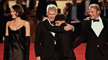 L'un a 16 ans, l'autre 80. Harrison Ford a été enlacé par le jeune acteur français Ethann Isidore sur le tapis rouge, avant la projection du 5e opus des aventures d'Indiana Jones, "Indiana Jones et le Cadran de la Destinée". Dans ce film, le plus célèbre des archéologues est rejoint par Phoebe Waller-Bridge et Mads Mikkelsen. (LOIC VENANCE / AFP)