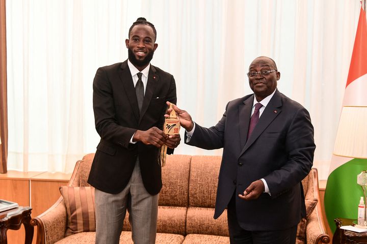 Cheick Cissé présente sa médaille de champion du monde 2023 au vice-président de la Côte d'Ivoire, Tiémoko Meyliet Koné, à Abidjan, le 23 juin 2023. (SIA KAMBOU / AFP)