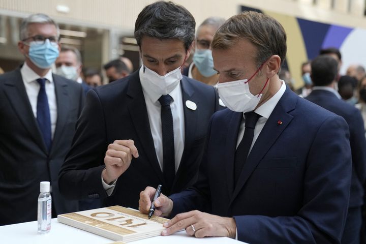 Le président Emmanuel Macron (à d.),&nbsp;au côté du responsable de Paris 2024 Tony Estanguet (à g.), signe une plaque lors de sa visite au siège du Comité d'organisation des Jeux olympiques et paralympiques de Paris 2024, à Saint-Denis, le 14 octobre 2021. (FRANCOIS MORI / POOL / AFP)