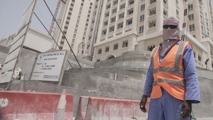 Un travailleur migrant employé dans le BTP pose devant le chantier d'un hôtel niché sur l'île artificielle The Pearl, au nord de Doha (Qatar), le 18 juin 2011. (SAM TARLING / CORBIS NEWS / GETTY IMAGES)