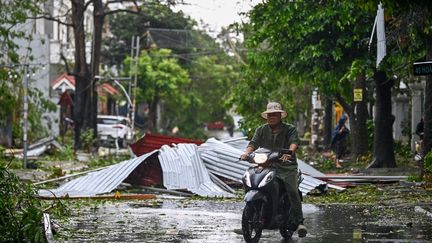 Un homme passe en scooter devant des débris dans une rue après que le super typhon Yagi a frappé la ville de Hai Phong, au Vietnam, le 7 septembre 2024. (NHAC NGUYEN / AFP)