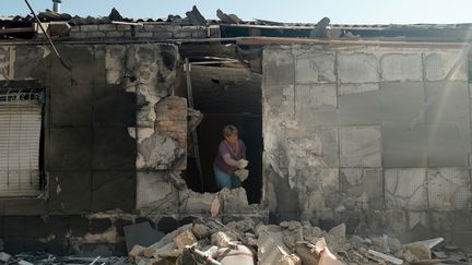 Une habitante de la région de Kherson dans un bâtiment éventré après une frappe de missile russe, le 14 août 2023. (ALEXEI  SANDAKOV / AFP)