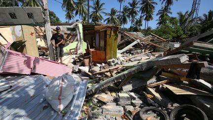 Un homme marche dans les décombres de sa maison, après le séisme à Lombok (Indonésie), le 11 août 2018. (KOJI ITO / YOMIURI)