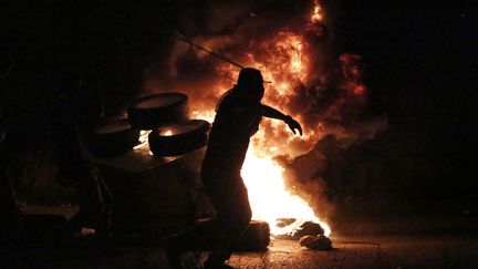 Un Palestinien lance des pierres sur des soldats isra&eacute;liens lors d'affrontements &agrave; Ramallah, en Cisjordanie occup&eacute;e, le 4 octobre 2015. (ABBAS MOMANI / AFP)