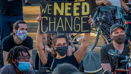 Un participant tenant un panneau "We Need Change" lors d'une manifestation à Brooklynn. (ERIK MCGREGOR / LIGHTROCKET)