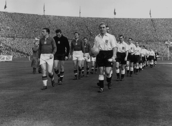 Les équipes hongroise (à gauche) et anglaise (à droite) entrent sur la pelouse de Wembley (Londres) pour le "match du siècle", le 25 novembre 1953. (WILLIAM VANDERSON / HULTON ARCHIVE / GETTY IMAGES)