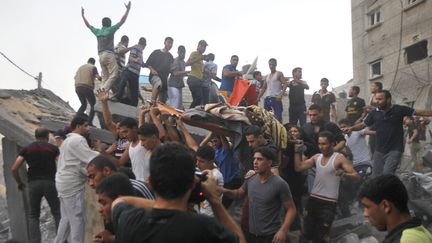 Des Palestiniens d&eacute;gageant des corps des ruines d'une maison bombard&eacute;e par l'arm&eacute;e isra&eacute;lienne, le 11 juillet 2014 &agrave; Rafah, dans la bande de Gaza. (SAID KHATIB / AFP)