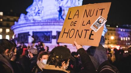 Un manifestant tenant une pancarte sur laquelle il est écrit "La nuit de la honte" sur la place de la République&nbsp;le 24 novembre pour dénoncer l'évacuation violente d'un camp de migrants lundi. (SAMUEL BOIVIN / NURPHOTO / AFP)