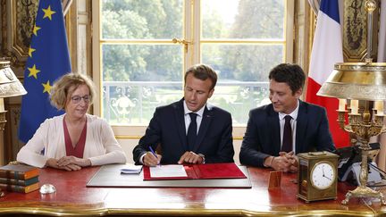 Emmanuel Macron signe la loi avenir professionnel, entouré par Muriel Pénicaud et Benjamin Griveaux à l'Elysée, le 5 septembre 2018.&nbsp; (THIBAULT CAMUS / AFP)