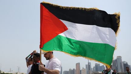 Un homme porte un drapeau palestinien en se rendant à la mosquée mosquée Imam Mohammad ben Abdel Wahab, à Doha, lors des obsèques du chef du Hamas, Ismail Haniyeh, le 2 août 2024. (KARIM JAAFAR / AFP)