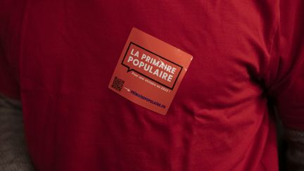 Le logo&nbsp;de la Primaire populaire sur un militant, le 30 janvier 2022, à Paris. (CORINNE SIMON / HANS LUCAS / AFP)