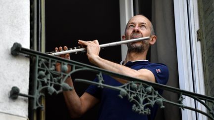 Un homme joue de la musique à sa fenêtre à Nancy lors de l'épidémie de coronavirus. (ALEXANDRE MARCHI / MAXPPP)