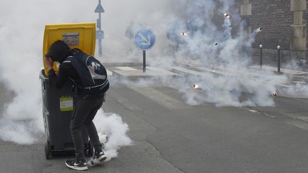 Un manifestant se protège des grenades lacrymogènes derrière une poubelle le 17 mai 2016 à Rennes (Ille-et-Vilaine) lors d'une manifestation contre la loi Travail. (DAMIEN MEYER / AFP)