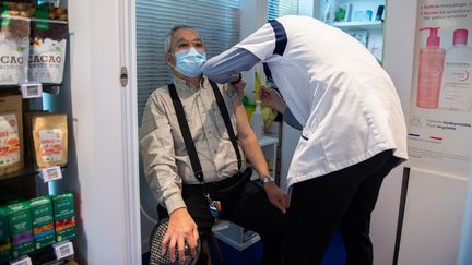 Un pharmacien injecte une dose de vaccin contre le Covid-19 à un patient, à Paris, le 12 mars 2021. (MARTIN BUREAU / AFP)