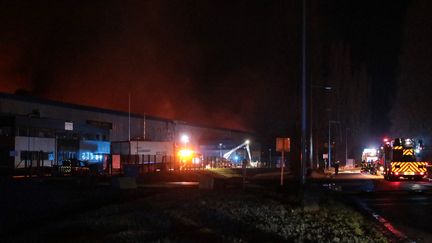 Plus d'une centaine de pompiers étaient toujours mobilisés sur l'incendie des entrepôts de Bolloré Logistics, à Grand-Couronne (Seine-Maritime), mardi 17 janvier 2022. (LOU BENOIST / AFP)