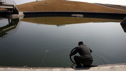 Un gardien penché au-dessus du bassin où ont eu lieu les compétitions de kayak pendant les Jeux olympiques de Pékin en 2008. Cet endroit, photographié ici en mars 2012, est à présent abandonné.  (DAVID GRAY / REUTERS)