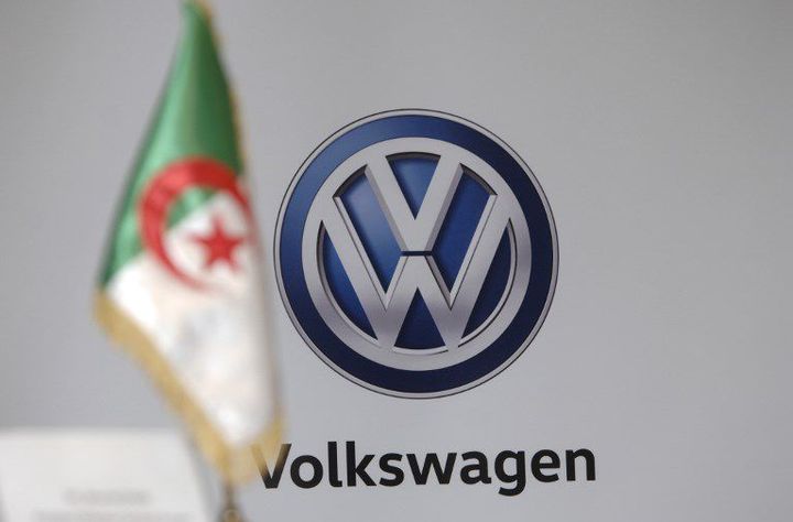 Le drapeau algérien devant le logo de Volkswagen lors de la signature d'un protocole d'accord entre les deux parties le 27 novembre 2016 à Alger. (AFP - RYAD KRAMDI)