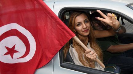 26 octobre 2014. Une Tunisienne brandit le drapeau de la Tunisie et forme le «V» de la victoire après avoir voté lors des premières élections législatives post-révolution. 
 (AFP PHOTO / FADEL SENNA)