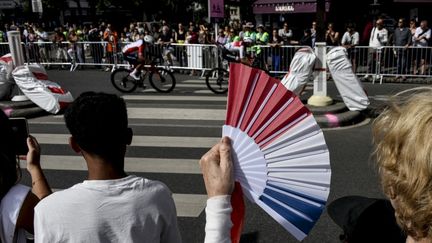 Des passants regardent la course cycliste féminine des Jeux olympiques, à Paris, le 4 août 2024. (MAGALI COHEN / HANS LUCAS / AFP)