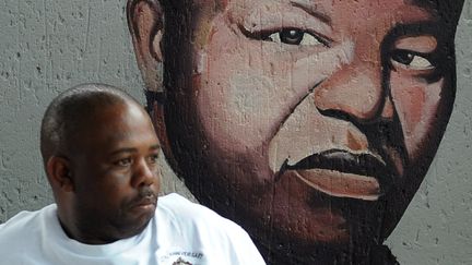 Un habitant de Soweto devant un portrait de Nelson Mandela, le 29 mars 2013, en Afrique du Sud. (ALEXANDER JOE / AFP)