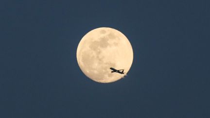 Un avion passe devant la Lune dans le ciel de Manhattan à New York, le 28 février 2018. (WILLIAM VOLCOV / BRAZIL PHOTO PRESS)