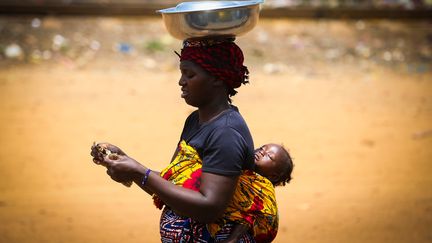 Une femme avec son bébé sur le dos à Conakry, la capitale de la Guinée. (OKAN OZER / ANADOLU AGENCY)