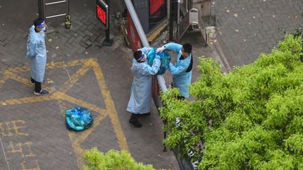 Un garde, portant un équipement anti Covid-19, récupère des colis à l'entrée d'une résidence pendant un nouveau confinement, à Shanghai (Chine), le 8 avril 2022. (HECTOR RETAMAL / AFP)