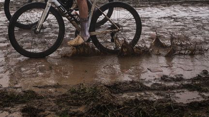 Le coureur d'AG2R Citroën Lawrence Naesen traverse un des secteurs pavés gorgé d'eau de Paris-Roubaix 2021, le 3 octobre (ANNE-CHRISTINE POUJOULAT / AFP)