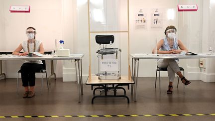Masques, visières, parois en plexiglas : un dispositif sanitaire complet était mis en place dans ce bureau de vote parisien, le 28 juin 2020, pour le second tour d'élections municipales perturbées par la crise sanitaire. (BERTRAND GUAY / AFP)